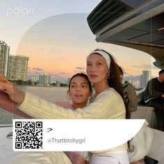 two women taking a selfie while on a boat in the water with buildings in the background