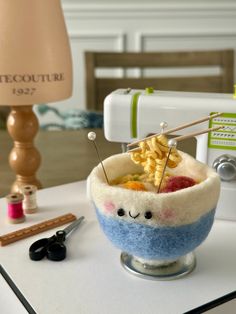 a bowl filled with food sitting on top of a table next to a sewing machine