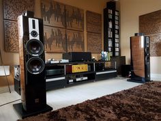 a living room with speakers and bookshelves in the corner on carpeted flooring