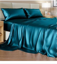 a bed with teal colored sheets and pillows on top of it, next to a night stand