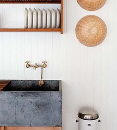 a kitchen sink and shelves with plates on the wall