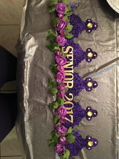 purple flowers and green leaves are arranged on a silver tablecloth that says, happy birthday