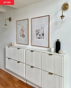 two framed pictures hang on the wall above a white dresser with gold handles and drawers