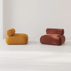 two different colored couches sitting next to each other on a white floor in an empty room