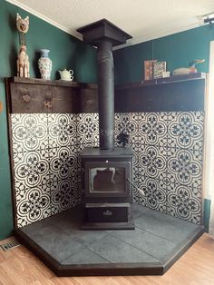 an old fashioned stove sits in the corner of a room with green walls and tile