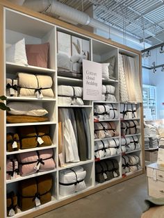 the shelves are filled with many different types of blankets and pillows, all in white