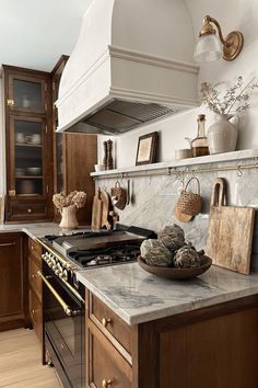 a kitchen with marble counter tops and wooden cabinetry, along with hanging utensils