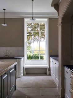 an empty kitchen with large windows and tile flooring