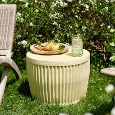 a plate of food sitting on top of a table in the grass next to two chairs