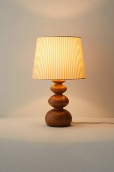 a lamp that is sitting on top of a table next to a white wall and floor