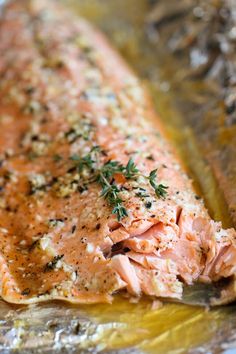 a piece of salmon on a foil pan with seasoning sprinkled on top