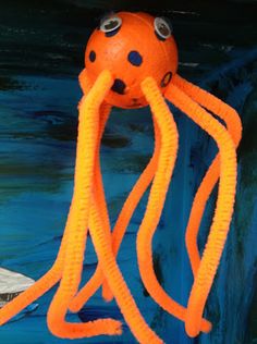 an orange and black octopus toy with eyes on it's head sitting on a blue surface