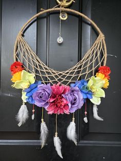 a wreath with flowers and feathers hanging from the front door