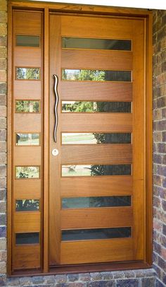 a modern wooden door with glass panels on the side and brick wall in front of it