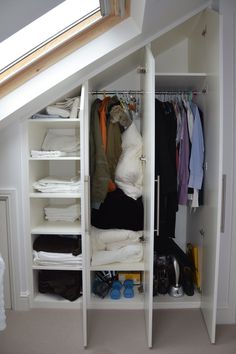 an attic closet with clothes and shoes in it