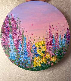 a painting on a wall with flowers painted on the bottom and pink sky in the background