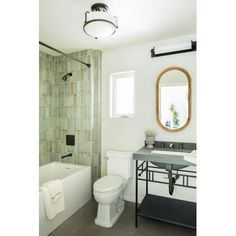 a white toilet sitting next to a bath tub under a bathroom mirror above a sink