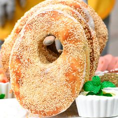 two bagels with sprinkles and mint leaves on the side next to small white dishes