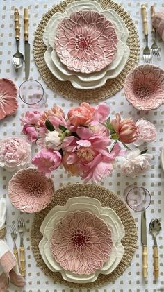 the table is set with pink flowers and silverware