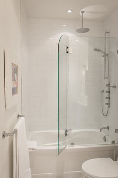 a bathroom with a toilet, shower and bathtub next to a white towel hanging on the wall