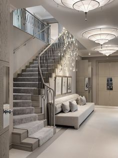 a living room filled with lots of furniture next to a stair case and chandelier