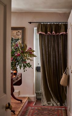 an open door leading to a living room with a rug on the floor and a potted plant next to it