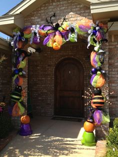 a house decorated for halloween with decorations on the front door and pumpkins hanging from it