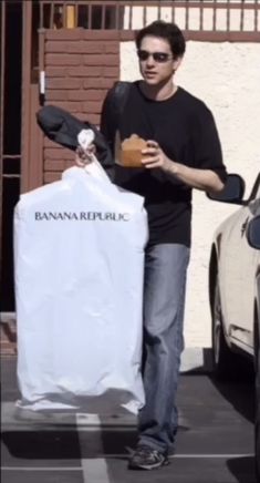 a man holding a white bag next to a parking meter