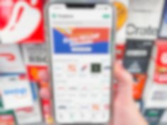 a person holding up a cell phone in front of a wall of vending machines