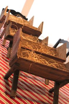 three wooden benches with straw in them on a striped rug