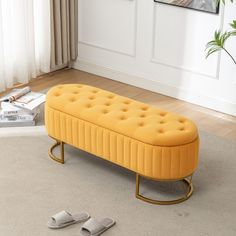 a yellow bench sitting on top of a white rug next to a pair of slippers