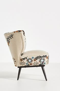 an upholstered chair sitting on top of a white floor next to a wall