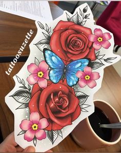 a person holding up a sticker with roses and butterflies on it next to a cup of coffee