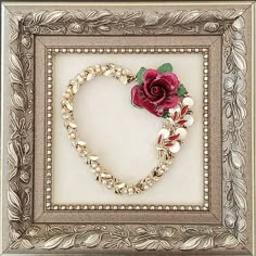 a heart shaped frame with a red rose on it and pearls around the edges,