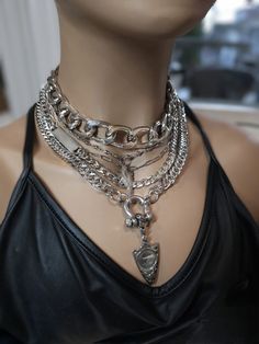 This handmade chunky stainless steel chain layered necklace set is a stunning piece of jewelry that is perfect for those who love bold and edgy accessories. This is two necklaces, the big chunky choker that is adjustable with a built-in extender, and the 4-strand drop festoon design necklace (also adjustable). Adding depth and dimension to the piece is a u lock and arrowhead pendant. Very punk, grunge aesthetic! All the chains are made of sturdy stainless steel, ensuring durability and longevity, and making it completely hypoallergenic, waterproof, and non tarnish. It will look exactly like this forever!  This necklace set is an excellent handmade gift for someone special. It is a perfect choice for those who love alternative and goth styles, as well as anyone who wants to make a statement Punk Grunge Aesthetic, Chunky Silver Jewellery, Edgy Necklace, Chain Layered Necklace, Handmade Aesthetic, Gothic Choker, Grunge Accessories, Chunky Choker, Goth Necklace