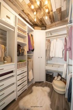 a white closet with lots of drawers and clothes hanging on the walls, along with an animal rug