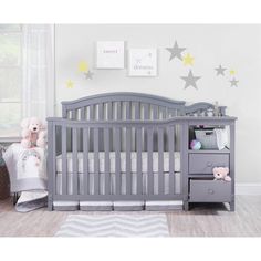 a baby crib with two teddy bears on the bed and a dresser in front of it