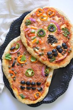 two pizzas sitting on top of a black plate