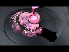 a pink candle sitting on top of a black table next to a glass bowl filled with liquid