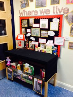 there is a black table with many pictures on it and some cards attached to the wall