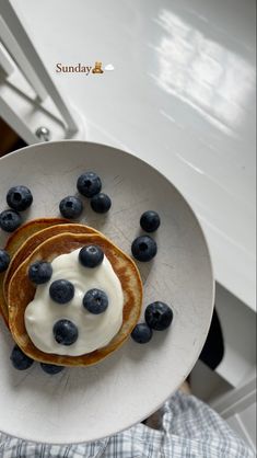 pancakes topped with blueberries and cream on a white plate