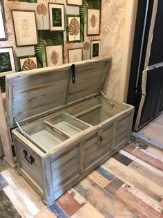 an open trunk sitting on top of a tiled floor next to pictures and framed art