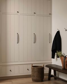 a large white closet with many doors and drawers next to a bench in a room