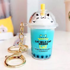 a cat milkshake and keychain sitting on a white table with a blue drink in it