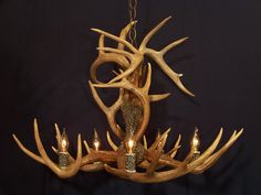 a chandelier made out of antlers with candles in the middle and one light on each side