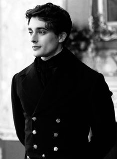 a black and white photo of a man in a suit with buttons on his lapel