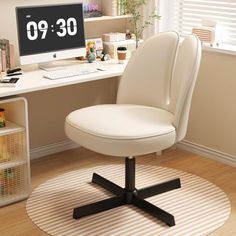 a white chair sitting in front of a computer monitor on top of a desk next to a window