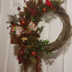 a christmas wreath hanging on the front door with red and green ornaments around it,