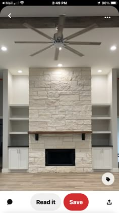 an empty living room with a ceiling fan and stone fireplace in the center, surrounded by built - in shelving units