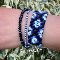 a woman's arm with three different bracelets on top of it and plants in the background